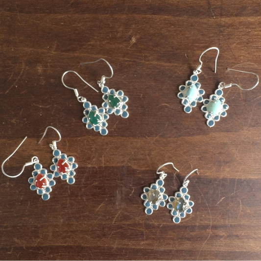 Set of floral-patterned silver earrings on a wooden surface